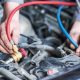 A closeup picture of a mechanic’s hands as they regas a vehicle’s air conditioning system.