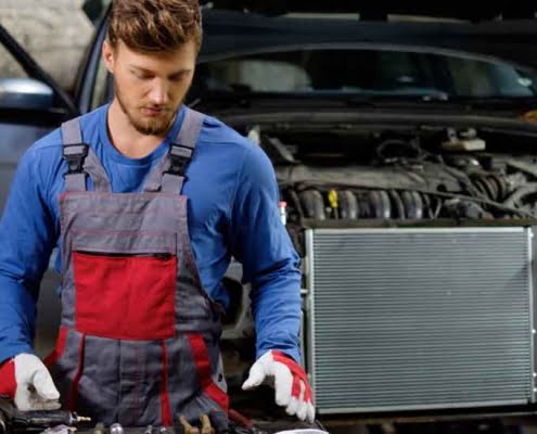 Mechanic inspecting car radiator for EV battery thermal management and cooling system service.