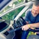 Man hoovering air vent in car