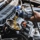 Car mechanic pouring engine oil into vehicle during doing car maintenance in garage